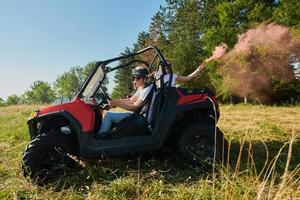 des gens excités s'amusant en profitant d'une belle journée ensoleillée tenant des torches colorées tout en conduisant une voiture buggy hors route photo