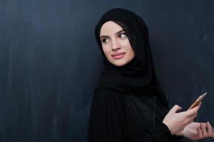 jeune femme d'affaires musulmane en vêtements traditionnels ou abaya à l'aide d'un smartphone photo