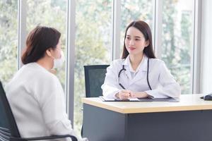 une femme médecin asiatique donne des suggestions d'informations sur les soins de santé à son patient dans la salle d'examen de l'hôpital. photo