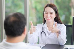 une belle femme médecin asiatique sourit et montre un signe de bruit ou très bien avec son patient en raison de ses soins de santé à l'hôpital. photo