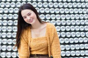 belle femme asiatique aux cheveux longs noirs en manteau jaune est assez souriante. photo