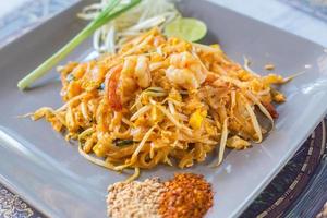 nouilles de riz frites aux crevettes pad thai est un aliment de rue de la thaïlande servi avec des germes de soja frais et des cacahuètes moulues comme garniture. photo