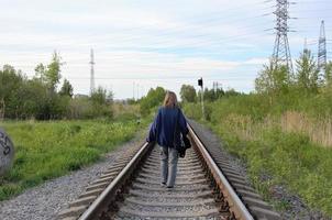 un adolescent marche sur les rails devant photo