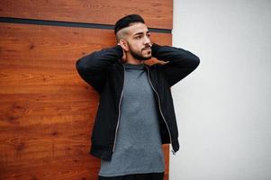 portrait d'un homme à la barbe arabe élégant portant un col roulé gris et un jaket noir. mec modèle arabe. photo