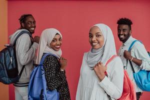 un groupe d'étudiants musulmans africains avec des sacs à dos posant sur fond rose. le concept d'éducation scolaire. photo