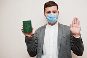 homme européen en tenue de soirée et masque facial, montre le passeport azerbaïdjanais avec la main du panneau d'arrêt. verrouillage du coronavirus dans le concept de pays d'europe. photo