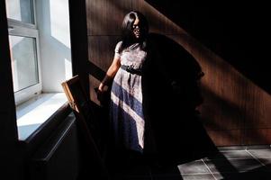 jeu avec les ombres. portrait de mode d'une femme afro-américaine en robe longue et lunettes à l'intérieur. photo