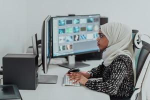 jeune femme d'affaires musulmane moderne afro-américaine portant un foulard dans un lieu de travail créatif et lumineux avec un grand écran. photo