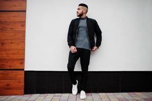 portrait d'un homme à la barbe arabe élégant portant un col roulé gris et un jaket noir. mec modèle arabe. photo