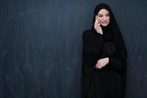 jeune femme d'affaires musulmane en vêtements traditionnels ou abaya à l'aide d'un smartphone photo