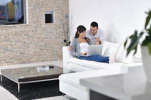un couple joyeux se détend et travaille sur un ordinateur portable dans une maison moderne photo