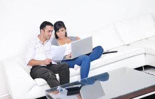 un couple joyeux se détend et travaille sur un ordinateur portable dans une maison moderne photo