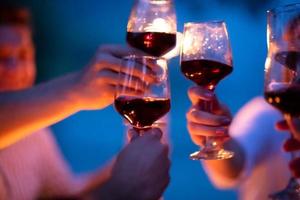 amis portant un verre de vin rouge lors d'un dîner français en plein air photo