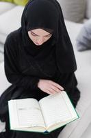 jeune femme musulmane lisant le coran à la maison photo