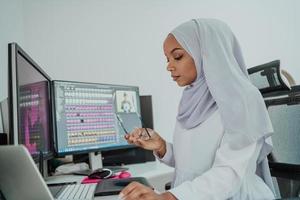 jeune femme d'affaires musulmane moderne afro-américaine portant un foulard dans un lieu de travail créatif et lumineux avec un grand écran. photo