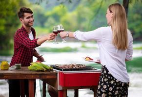 couple heureux portant un verre de vin rouge lors d'un dîner français en plein air photo