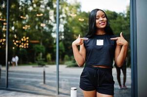 vêtements de femme afro-américaine féministe à la mode en t-shirt et short noirs, posés à l'extérieur. photo