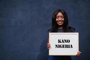 une femme africaine tient un tableau blanc avec inscription kano nigeria. concept de ville la plus peuplée d'afrique. photo