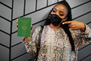 une femme africaine portant un masque noir montre un passeport mauritanien en main. coronavirus en afrique, fermeture des frontières et quarantaine, concept d'épidémie de virus. photo