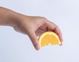 main serrant des fruits orange tranchés sur fond blanc. photo