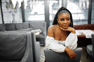 belle femme afro-américaine en blouse blanche et pantalon en cuir rouge pose au restaurant. photo