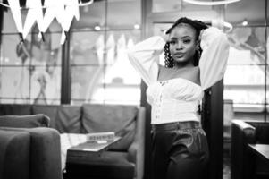 belle femme afro-américaine en blouse blanche et pantalon en cuir rouge pose au restaurant. photo