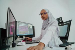 jeune femme d'affaires musulmane moderne afro-américaine portant un foulard dans un lieu de travail créatif et lumineux avec un grand écran. photo