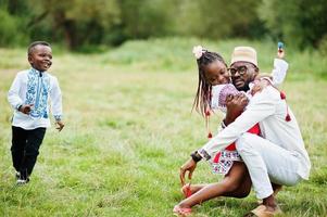 père africain avec des enfants en vêtements traditionnels au parc.
