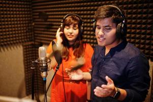 jeunes chanteurs asiatiques en duo avec microphone enregistrant une chanson dans un studio de musique d'enregistrement. photo