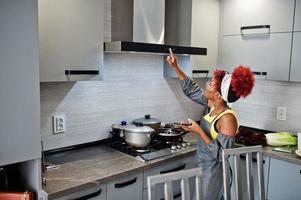 femme afro-américaine à la maison cuisine allumer la hotte. photo