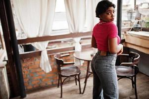 jeune femme afro-américaine urbaine en haut rose et jeans gris. mode afro femme chic. photo