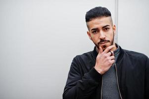 portrait d'un homme à la barbe arabe élégant portant un col roulé gris et un jaket noir. Guy modèle arabe contre le mur en acier. photo