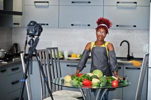 femme afro-américaine filmant son blog diffusé sur des aliments sains dans la cuisine à domicile. photo