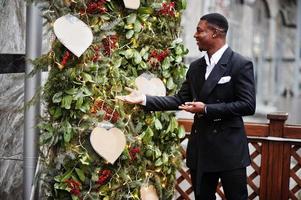 portrait de jeune et beau homme d'affaires afro-américain en costume près des décorations d'arbre du nouvel an. photo