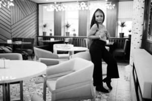 portrait d'une jeune femme afro-américaine séduisante portant un pull vert et un jean noir posent au restaurant. photo