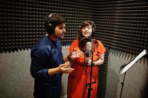 jeunes chanteurs asiatiques en duo avec microphone enregistrant une chanson dans un studio de musique d'enregistrement. photo