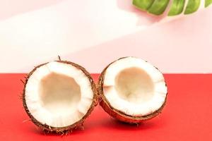 deux moitiés de noix de coco crue fraîche sur fond rouge avec des ombres claires en blanc. photo