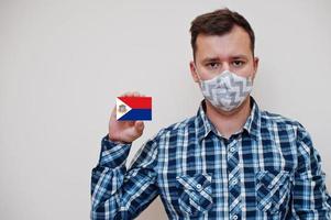 homme en chemise à carreaux montre la carte du drapeau de sint maarten à la main, porte un masque de protection isolé sur fond blanc. concept de coronavirus des pays américains. photo