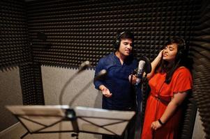 jeunes chanteurs asiatiques en duo avec microphone enregistrant une chanson dans un studio de musique d'enregistrement. photo