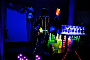 barman professionnel et spectacle de lumière led. silhouette de barman moderne secouant la boisson au bar à cocktails de nuit. photo