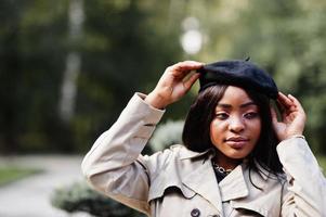 portrait en gros plan d'une femme afro-américaine à la mode portant un béret et un manteau posant à l'extérieur. photo