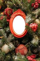 gros plan sur un sapin de noël décoré de boules de couleurs rouge, argent et maquette de cadres photo vides. concept festif de carte de voeux d'hiver