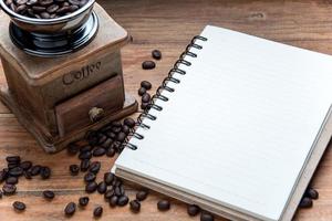 portable avec grain de café et moulin à café sur table en bois. photo