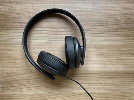 écouteurs circum-auriculaires noirs posés sur un bureau en bois photo