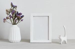 cadre de maquette blanc avec vase et statuette de chat. photo