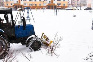 le tracteur dégage la route de la neige en hiver lors d'une chute de neige. photo