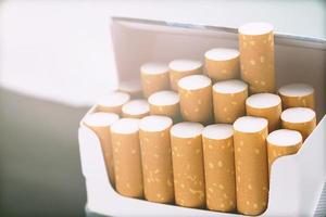 Décollez-le du paquet de cigarettes en fumant une cigarette sur fond blanc. photo