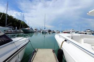 de nombreux yachts de luxe flottent sur une mer cristalline dans le club de la baie de la marina, un bateau privé coûteux reste calme dans la jetée d'amarrage sous le ciel bleu d'été océan vert photo