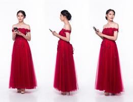 corps de pleine longueur d'une belle femme asiatique portant une robe de soirée rouge à paillettes, téléphone internet en état de marche photo