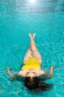 belle fille sexy avec un corps mince en maillot de bain jaune bikini, femme asiatique relaxante dans la piscine bleue de l'hôtel spa de villégiature en vacances de voyage, espace de copie photo
